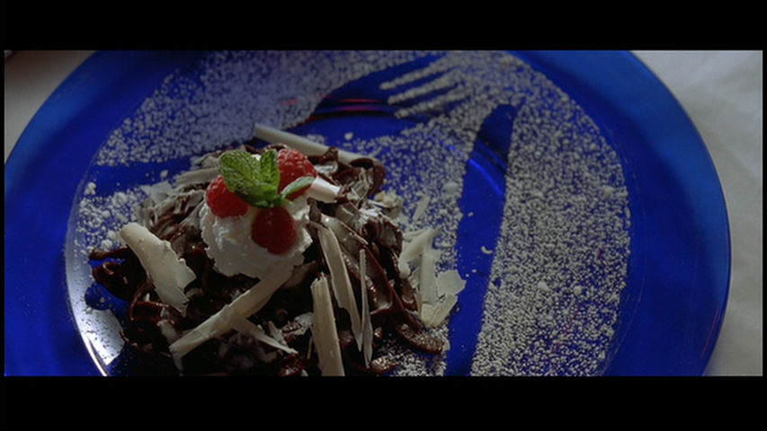 Camera tilts up to food dish (with red, white, and blue coding), associating eating (consumption) with Patrick's imagined murder of Christie