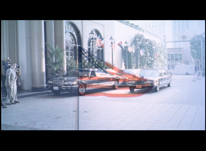 Dissolve of flag into limousines, "Do Not Enter" sign symbolizing the transnational corporate takeover of our democracy